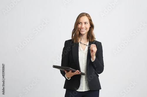Portrait of a beautiful and flirting business woman looking gorgeous to the left holding a folder or computer and glasses in her hands  photo