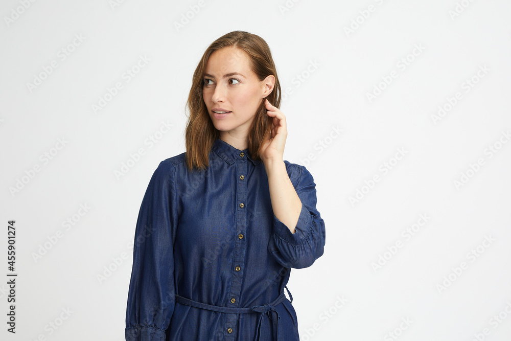 Portrait of a young beautiful woman in denim touching her hair and looking to the left Portrait of a young beautiful woman in denim touching her hair and looking to the left