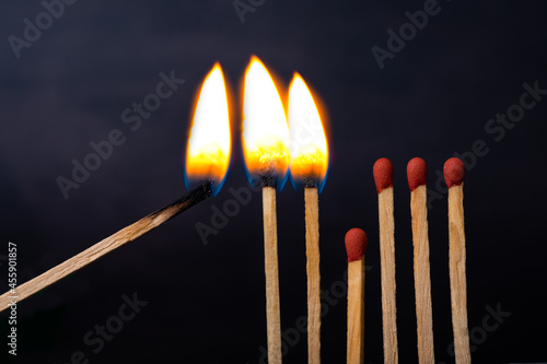 Burnt matches and whole matches on dark black background. The spread of fire. One whole match to stop the fire. Stop destruction concept