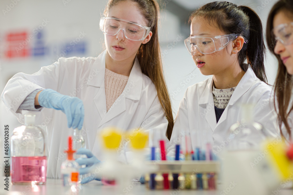 Girl students conducting scientific experiment in laboratory classroom Girl students conducting scientific experiment in laboratory classroom