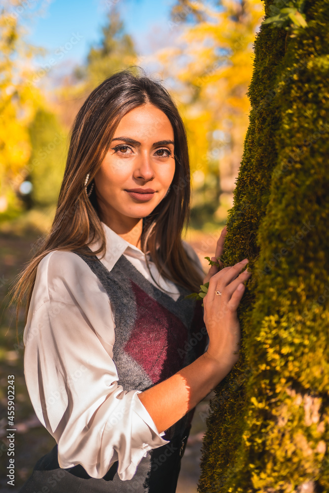 Lifestyle, a young brunette Caucasian college girl, in a park next to a tree one autumn afternoon in a fashionable pose Lifestyle, a young brunette Caucasian college girl, in a park next to a tree one autumn afternoon in a fashionable pose