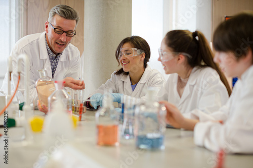 Male teacher and students conducting scientific experiment in laboratory classroom
