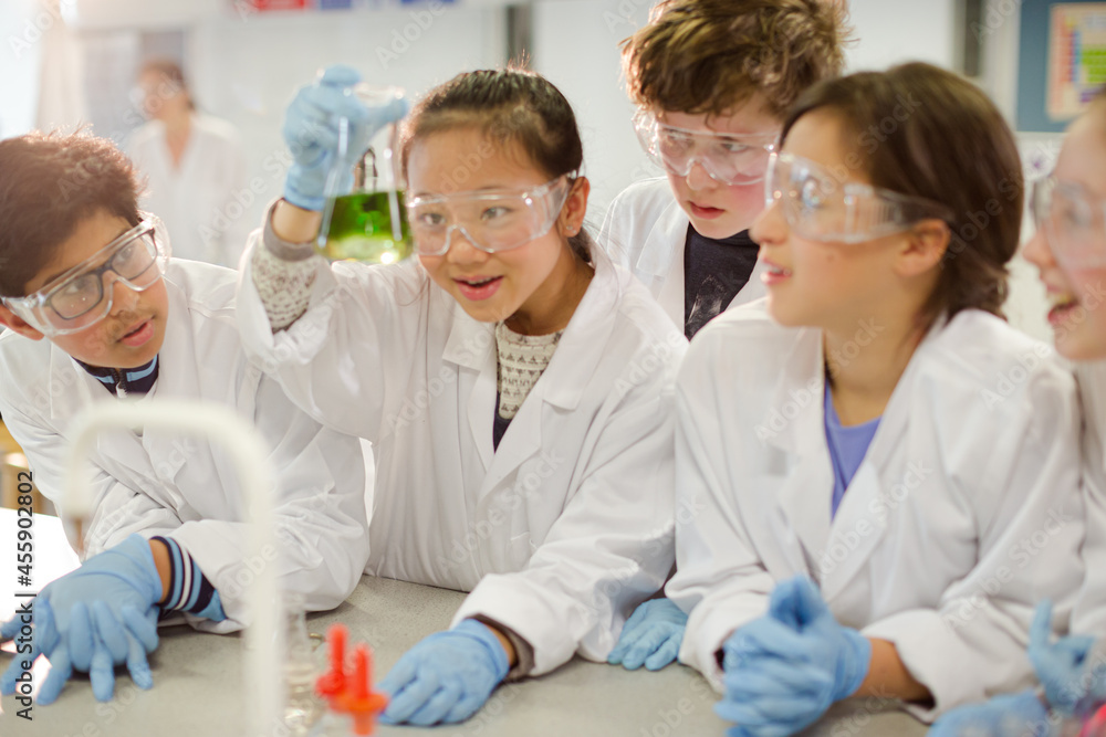 Curious students conducting scientific experiment, examining liquid in beaker in laboratory classroom Curious students conducting scientific experiment, examining liquid in beaker in laboratory classroom