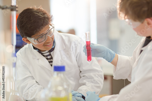 Boy students examining liquid in test tube  conducting scientific experiment in laboratory classroom