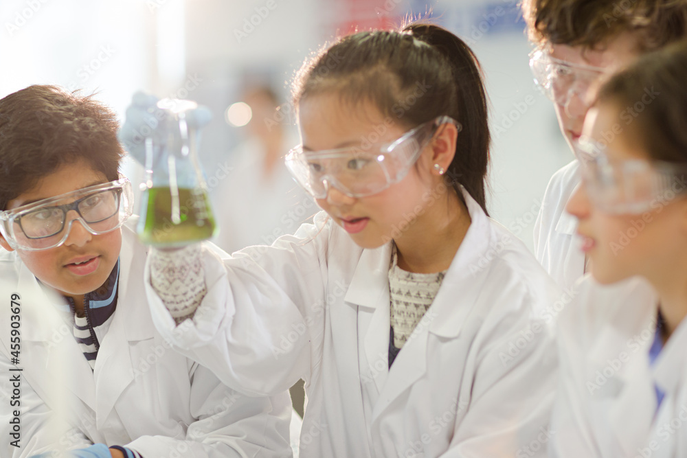 Curious students conducting scientific experiment, examining liquid in beaker in laboratory classroom Curious students conducting scientific experiment, examining liquid in beaker in laboratory classroom