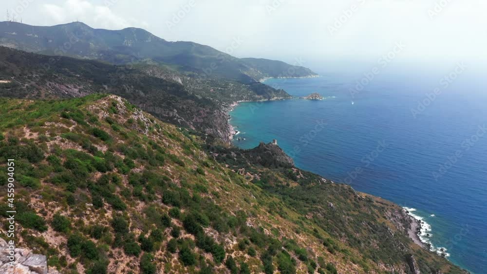 Aerial view of rocky coastline with green bushes, down blue sea. White rocks, trees. waves crashing against an empty beach, blue sky in a summer day in Italy Aerial view of rocky coastline with green bushes, down blue sea. White rocks, trees. waves crashing against an empty beach, blue sky in a summer day in Italy
