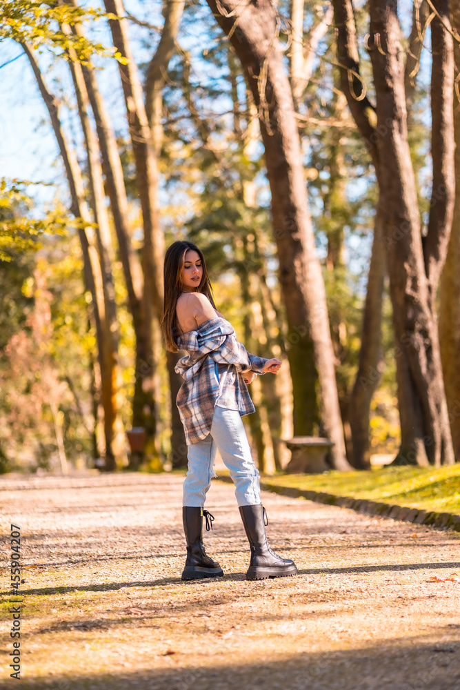 Lifestyle, a young Caucasian brunette girl in a plaid wool sweater and ripped jeans in a park in autumn Lifestyle, a young Caucasian brunette girl in a plaid wool sweater and ripped jeans in a park in autumn