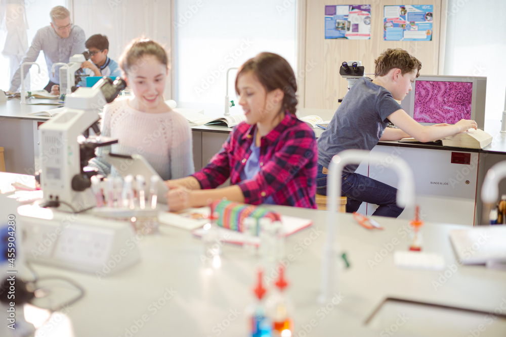 Girl students using microscope, conducting scientific experiment in laboratory classroom Girl students using microscope, conducting scientific experiment in laboratory classroom