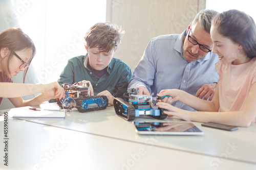 Male teacher and students playing with robot in classroom