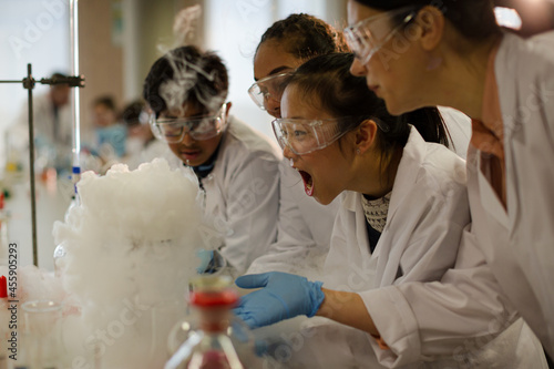 Female teacher and students watching scientific experiment chemical reaction in laboratory classroom photo