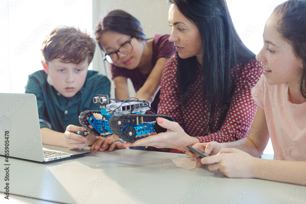 Fototapeta premium Female teacher and students playing with robot in classroom