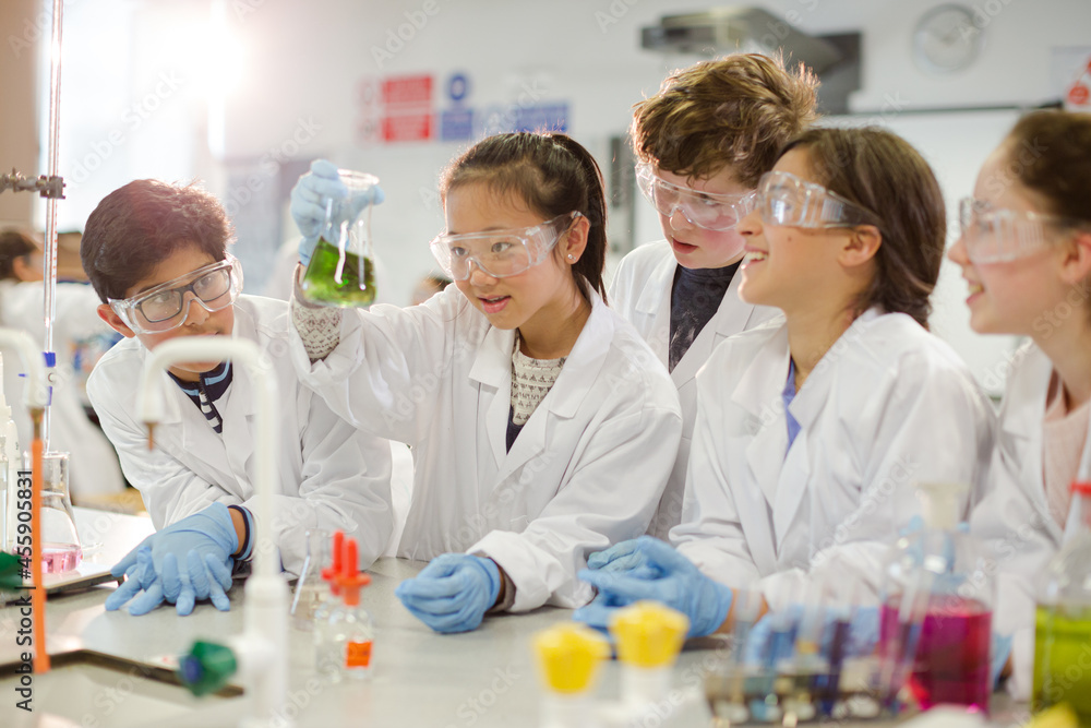 Curious students conducting scientific experiment, examining liquid in beaker in laboratory classroom Curious students conducting scientific experiment, examining liquid in beaker in laboratory classroom