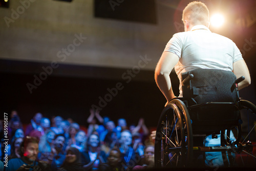 Audience watching speaker in wheelchair talking on stage