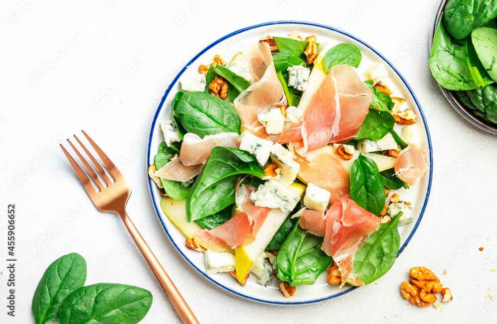 Pear salad with prosciutto, blue cheese, spinach, walnuts on white background, top view, copy space Pear salad with prosciutto, blue cheese, spinach, walnuts on white background, top view, copy space