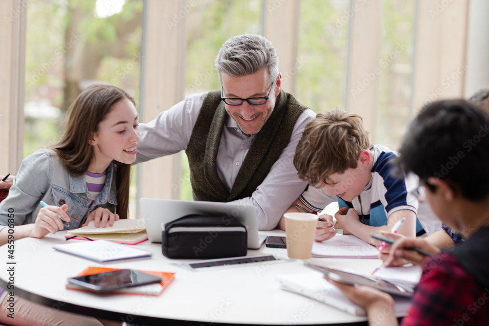 Fototapeta premium Male teacher and students using laptop at table