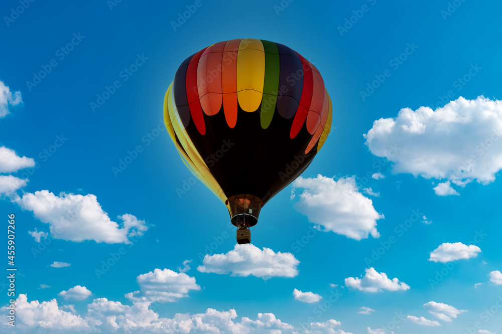 Fototapeta premium Colorful hot air balloon flying against blue clouds sky. Beautiful Inspiration or travel background, fly above the clouds, colorful hot air balloon in blue sky