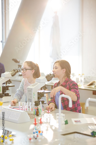Eager girl students behind microscopes in laboratory classroom