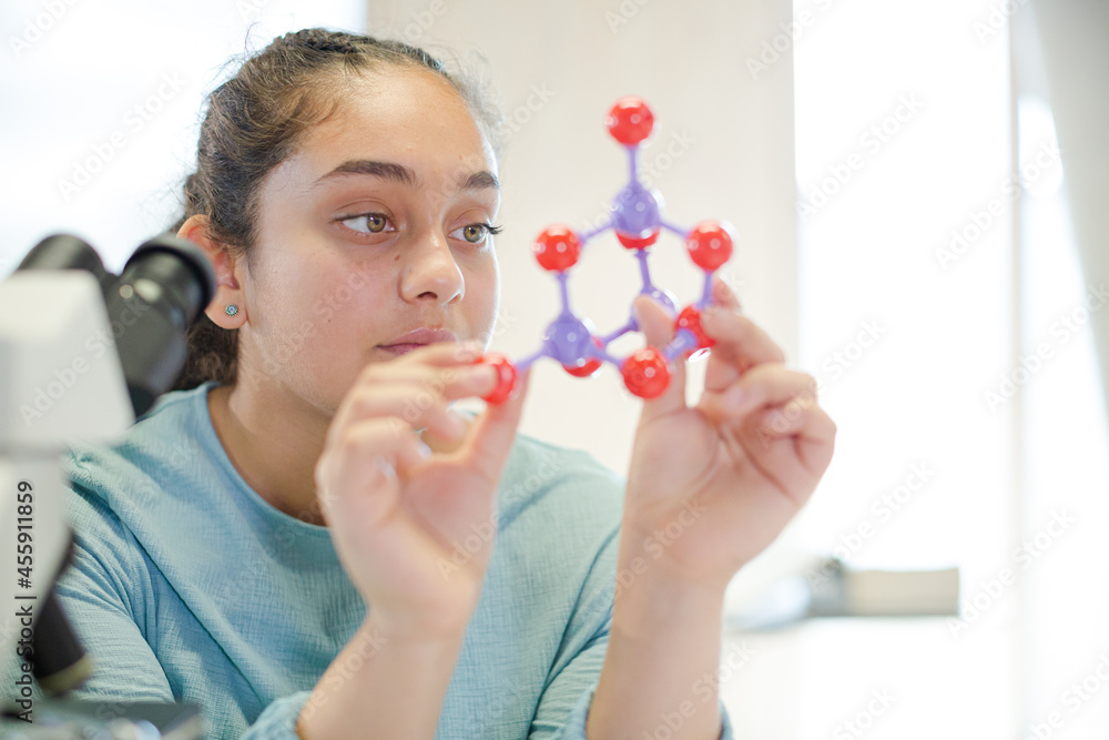Curious girl student examining molecular structure in laboratory classroom Curious girl student examining molecular structure in laboratory classroom