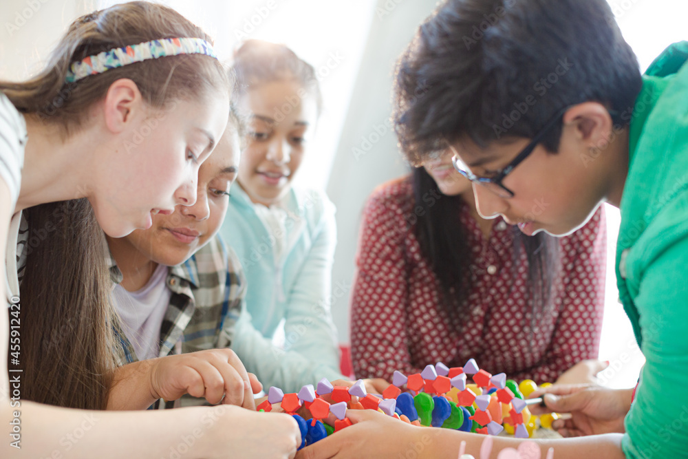 Female teacher and students examining DNA model in classroom Female teacher and students examining DNA model in classroom