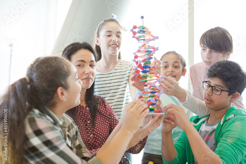 Female teacher and students examining DNA model in classroom