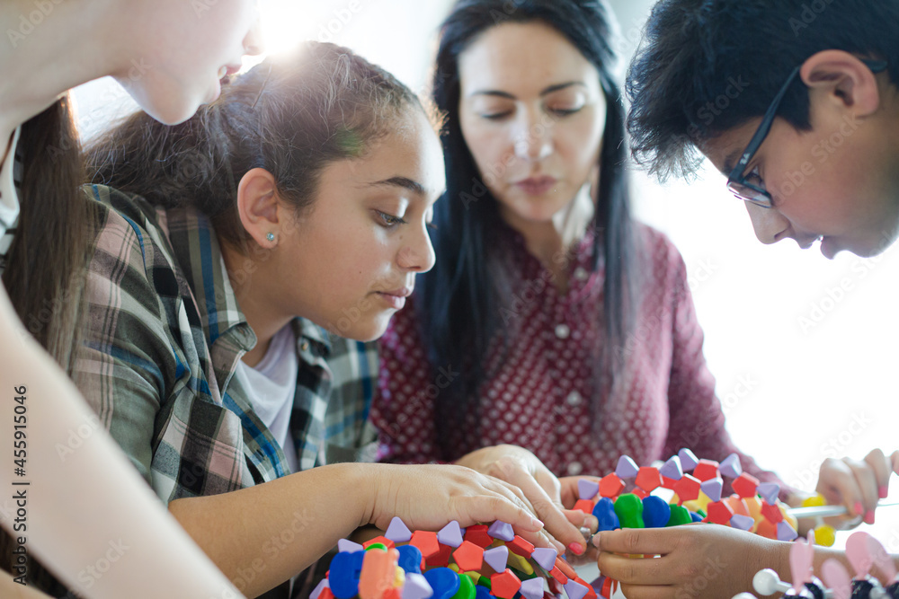 Female Teacher And Students Examining Dna Model In Classroom Stock 