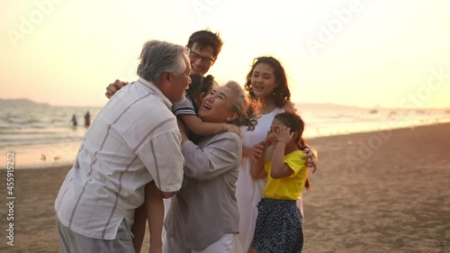 Happy big Asian family on beach holiday vacation. Multi-generation family holding hands and walking together on tropical beach at summer sunset. Family enjoy and having fun outdoor activity lifestyle.