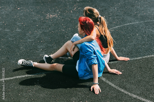 Teenage girls are sitting on a sports field in a park or a school stadium. Friends, friendship, time together