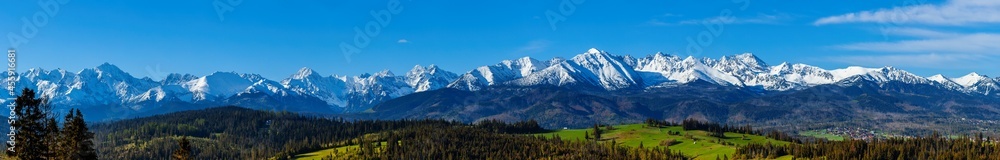 A beautiful panorama of the entire range of the Tatra Mountains. The colorful rays of the sun illuminate the snow-covered, white mountains. The view at sunrise. Poland - obrazy, fototapety, plakaty 
