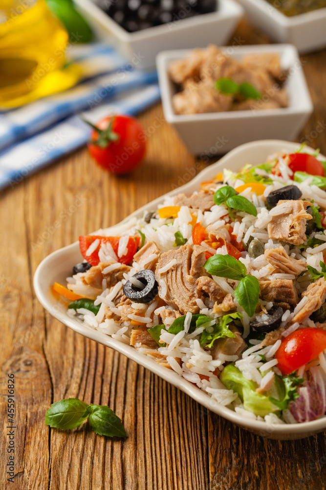 Italian tuna salad with rice, olives and capers. Front view. Natural wooden background. Italian tuna salad with rice, olives and capers. Front view. Natural wooden background.