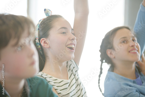 Eager  smiling students raising hands in classroom