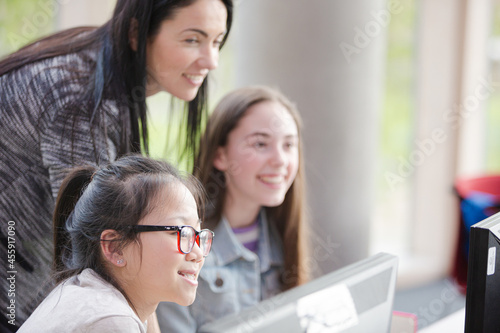 Female teacher and girl students using computer