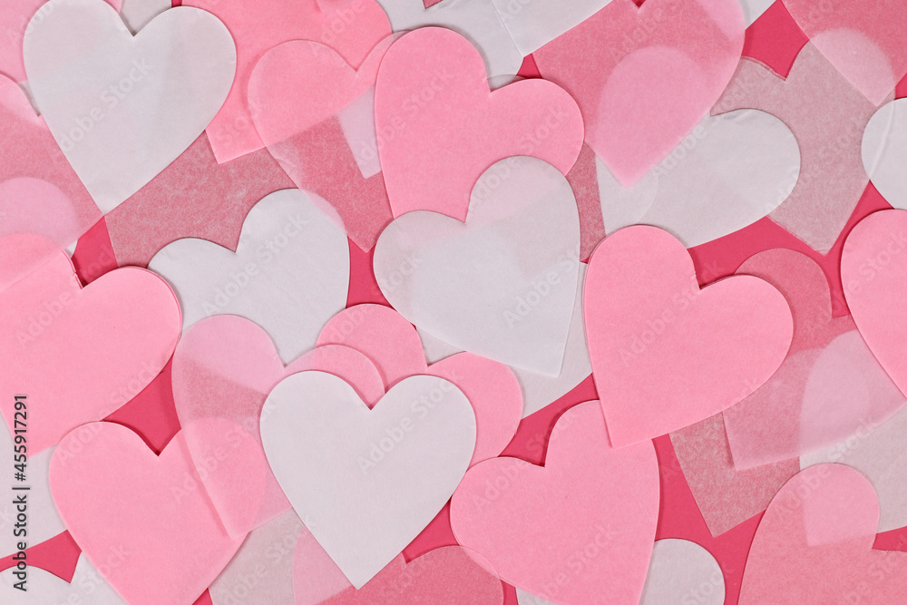 White and pink heart shaped paper confetti on pink background