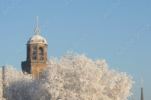 The tower of the Great Church in Deventer, the Netherlands, above trees covered with frost in winter photo