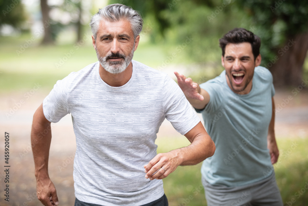 two friends running through the forest on a jogging trail two friends running through the forest on a jogging trail