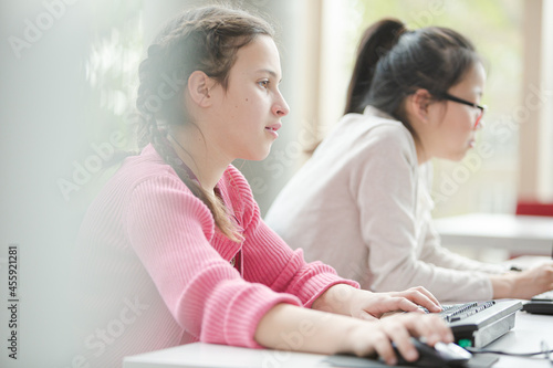 Girl students working at computer in library