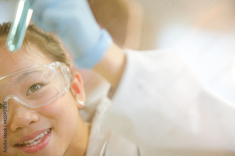 Fototapeta premium Girl students conducting scientific experiment, examining liquid in test tube in laboratory classroom
