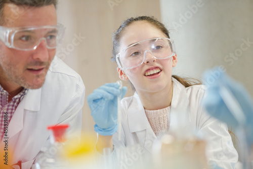 Male teacher and students conducting scientific experiment in laboratory classroom