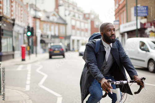African businessman commuting, riding bicycle on urban street
