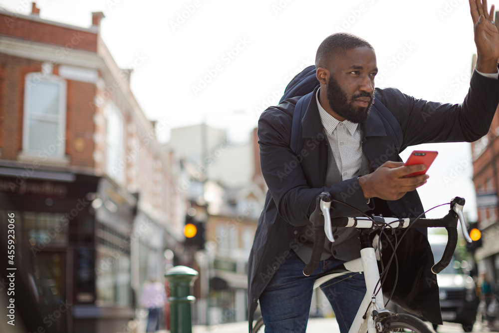 Young businessman commuting with bicycle, texting with cell phone on sunny urban street Young businessman commuting with bicycle, texting with cell phone on sunny urban street
