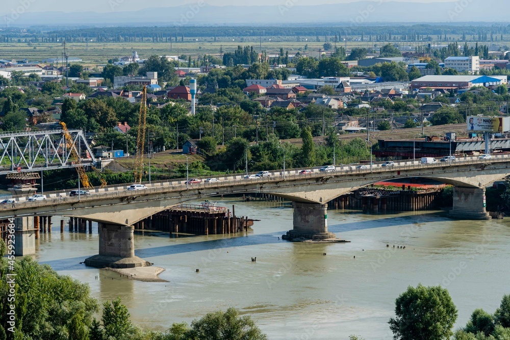 Traffic cars on emergency road bridge across Kuban River. In background is construction of new four-lane road bridge. On left is construction of railway bridge. Krasnodar, Russia - September 05, 2021