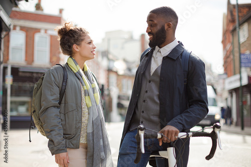 Smiling businessman with bicycle and woman on urban street