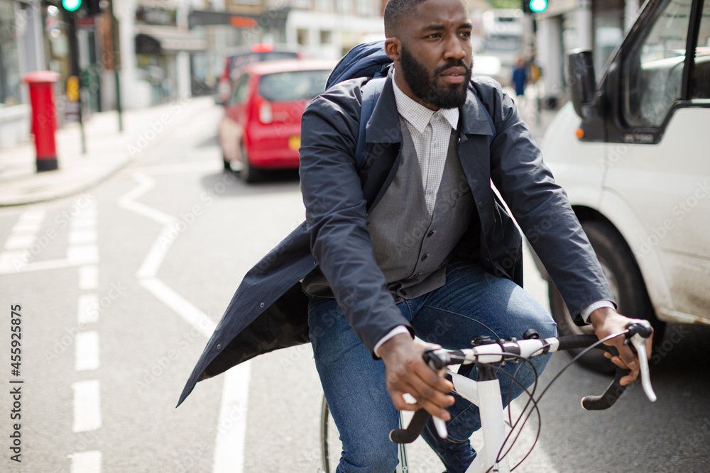 Young businessman commuting, riding bicycle on urban street Young businessman commuting, riding bicycle on urban street