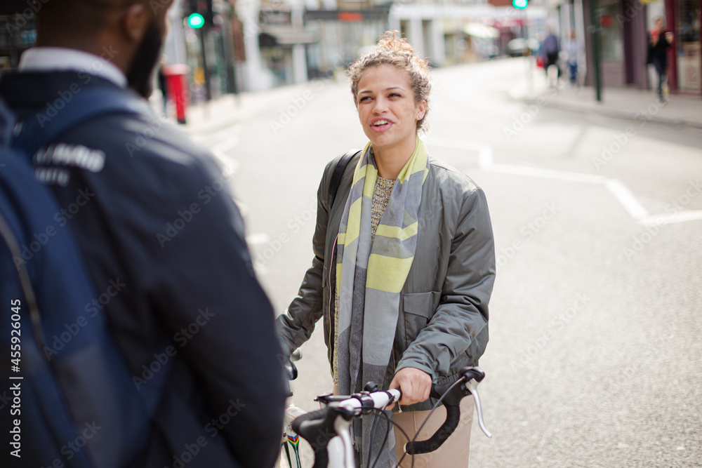 Obraz premium Friends with bicycle talking on sunny urban street