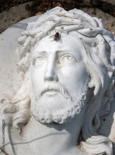 Statue of Jesus Christ with his eyes turned to his forehead where a fly sits.
