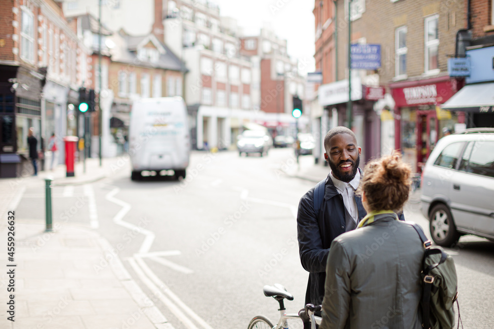 Smiling businessman with bicycle and woman on urban street