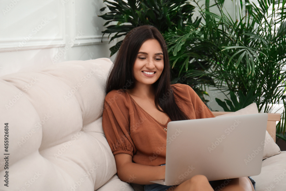 Beautiful woman using laptop on sofa in living room. Interior design Beautiful woman using laptop on sofa in living room. Interior design