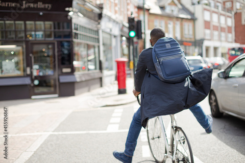 Playful young businessman commuting, riding bicycle on urban street