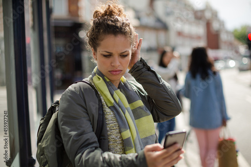 Photos Young woman texting on sunny urban street