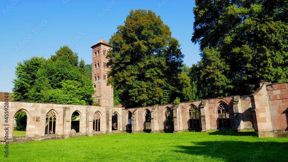 Ruine eines Kreuzgangs im Kloster Hirsau mit Turm im Schwarzwald  und Bäumen unter blauem Himmel