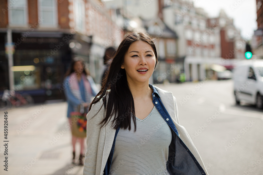Smiling, enthusiastic young woman walking on sunny urban street Smiling, enthusiastic young woman walking on sunny urban street